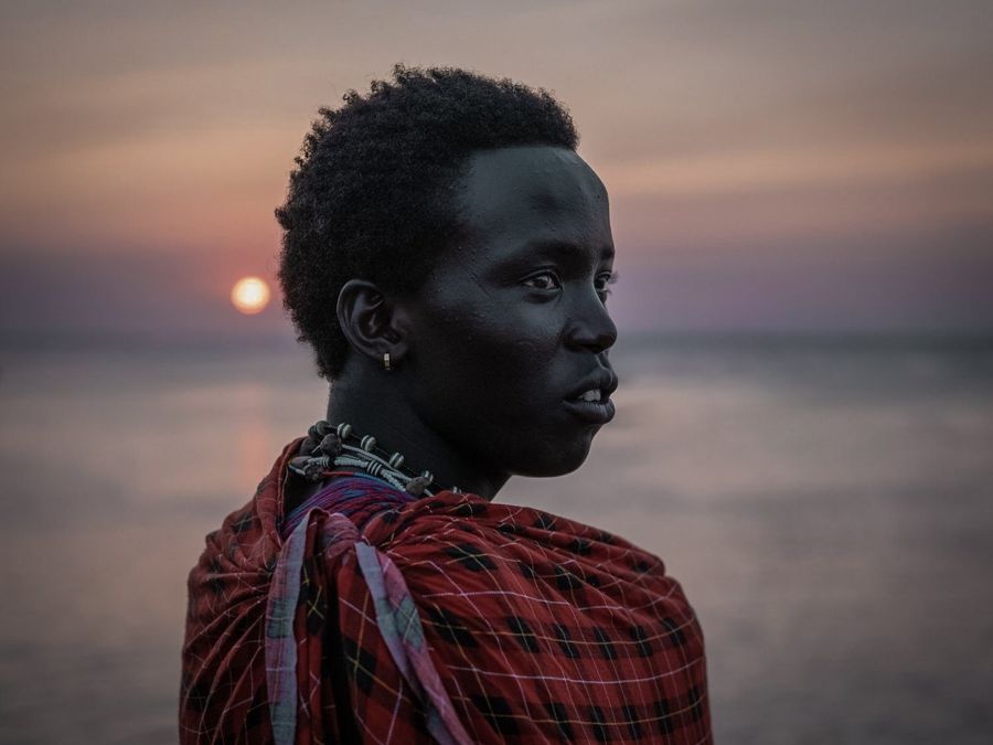 Portrait of a Maasai, Zanzibar, Tanzania: profile of a man in a red checked shuka against the sea at sunset. Photograph by Marcus Vallance.